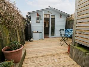 a backyard deck with a blue shed and a house at The Artists Cabin in Herne Bay