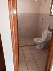 a bathroom with a toilet and a tiled floor at Tamara One Bedroom Apartment in Shanzu in Mombasa