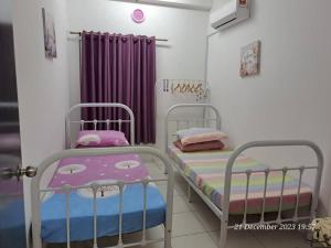 twee bedden in een kamer met paarse gordijnen bij İmpiana Homestay near PUTRAJAYA, CYBERJAYA, Musliem Only,WIFI,Netflix in Kampung Dengkil