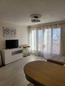 een woonkamer met een tv en een bank en een tafel bij Elégant apparemment 60m2 climatisé in Avignon