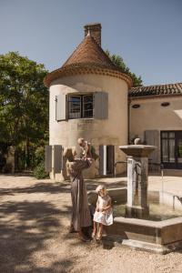 Une femme et une petite fille debout à côté d'une fontaine dans l'établissement Château Les Carrasses, à Capestang