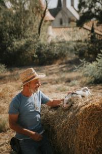 Un homme dans un chapeau caresse un bébé mouton dans l'établissement Château Les Carrasses, à Capestang