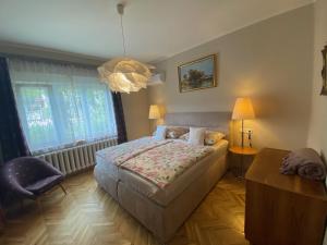 - une chambre avec un lit, une chaise et un lustre dans l'établissement Villa Trófea, à Hévíz