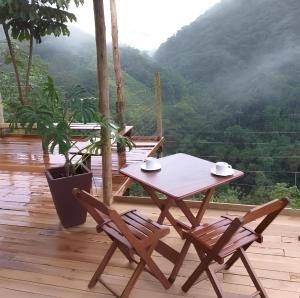 een tafel en stoelen op een terras met uitzicht op de bergen bij Pousada São Francisco PETAR in Iporanga