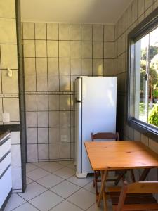 eine Küche mit einem Tisch und einem Kühlschrank in der Unterkunft Sítio Exclusivo em Marechal Floriano, Piscina, Sauna, Jacuzzi e Lago - Estrada Calçada a 200 metros da Rua Principal in Marechal Floriano
