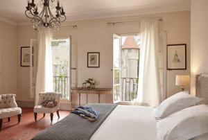 - une chambre avec un lit, une chaise et des fenêtres dans l'établissement Château Les Carrasses, à Capestang