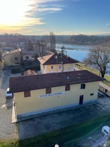 a white building with a red roof and a river at B&B Osteria dello sperone in Lonate Pozzolo