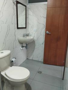 a bathroom with a toilet and a sink and a door at Hotel Colonial House in Pasto