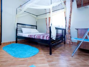 a bedroom with a canopy bed and a blue rug at Ivy Homes in Mukono