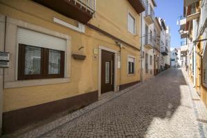 eine Kopfsteinpflasterstraße in einer Gasse zwischen zwei Gebäuden in der Unterkunft A Casinha Avó Mariana 53 in Nazaré