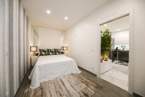 - une chambre blanche avec un lit et un tapis dans l'établissement A Casinha Avó Mariana 53, à Nazaré