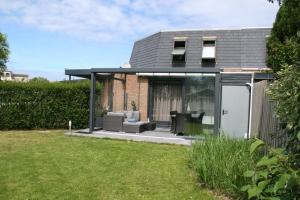 uma casa com uma extensão de vidro com um pátio em Zouterik 5* em Nieuwvliet