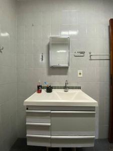 La salle de bains blanche est pourvue d'un lavabo et d'un miroir. dans l'établissement Chácara Recanto Solar, à Águas de Lindóia