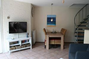 uma sala de estar com uma mesa e uma televisão em Zouterik 5* em Nieuwvliet