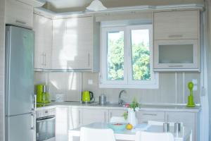 a kitchen with white cabinets and a window at Villa Orama in Nea Potidaea