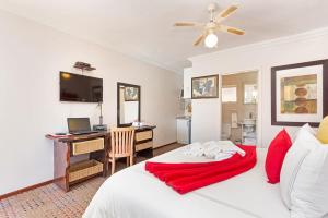a bedroom with a desk and a bed with a red blanket at Kwantu Guesthouse 1 in Cape Town