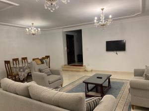 een woonkamer met banken en een tafel en een televisie bij Chelay Apartments in Caïro