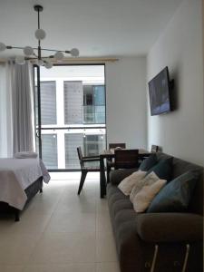 Una sala de estar con un sofá y un dormitorio. en Loft completo con balcón a 5 min de la playa, en Santa Marta