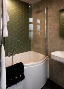 a bathroom with a bath tub and a sink at Amber Lights Coastal Getaway, Greatstone in Greatstone