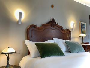 um quarto com uma cama com lençóis brancos e almofadas verdes em EVERGREEN GuestHouse em Vernon