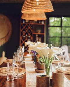 a long wooden table with glasses and flowers on it at Sambora Kinigi in Kinigi