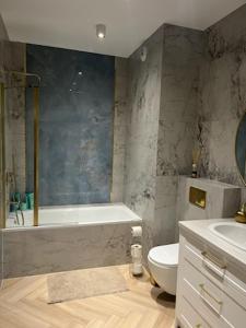 uma casa de banho com uma banheira, um WC e um lavatório. em Apartament Vulcano Komfort Nowy Ursus em Varsóvia