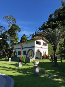マレシャウ・フロリアノにあるSítio Exclusivo em Marechal Floriano, Piscina, Sauna, Jacuzzi e Lago - Estrada Calçada a 200 metros da Rua Principalの庭のヤシの木がある白い家