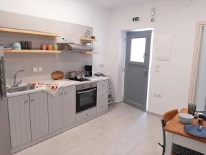 una cucina con mobili bianchi, un lavandino e un tavolo di Bright town house a Kampos Paros