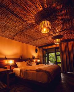 a bedroom with a bed with a wicker ceiling at Sambora Kinigi in Kinigi