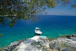 un barco sentado en el agua junto a la orilla en STONE VILLAGE, en Vela Luka