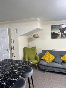 a living room with a table and a green chair at GM247 Nice Accommodation Stays in Wigan