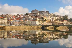 eine Stadt, die im Wasser mit einer Brücke reflektiert in der Unterkunft Casa do Museu in Coimbra