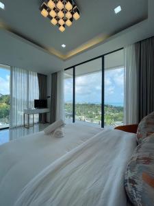 una grande camera da letto con un grande letto e ampie finestre di Villa Savoy Sharm Samui a Chaweng Noi Beach