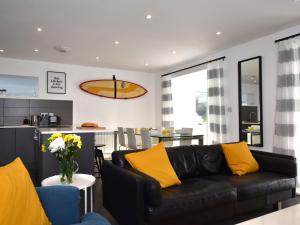 a living room with a black couch and yellow pillows at 3 Bed in Widemouth Bay 86151 in Marhamchurch