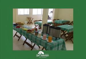 a table with a green table cloth with food on it at Pousada São Francisco PETAR in Iporanga