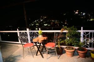 einen Tisch und zwei Stühle auf einem Balkon mit Pflanzen in der Unterkunft Plaza HomeStay in Masuri