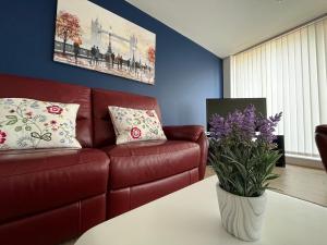 uma sala de estar com um sofá de couro vermelho e um vaso de flores em Central Darlington Large Penthouse Apartment em Darlington