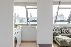 a kitchen with white cabinets and a green couch at Light-filled Primrose Hill Rooftop Retreat in London