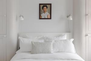 a bed with white pillows and a portrait of a woman at Light-filled Primrose Hill Rooftop Retreat in London