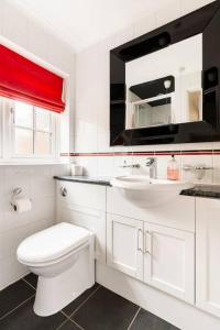 a white bathroom with a toilet and a sink at Arnica Cottage in Wells next the Sea