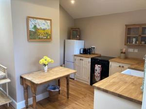a kitchen with a table and a refrigerator at Hen House: Private annexe on stunning farm in Melton Mowbray