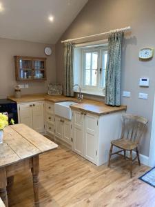 a kitchen with a sink and a table with a chair at Hen House: Private annexe on stunning farm in Melton Mowbray