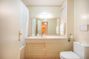 ein Badezimmer mit einem Waschbecken, einem WC und einem Spiegel in der Unterkunft Casa do Jardim- Aroeira in Aroeira