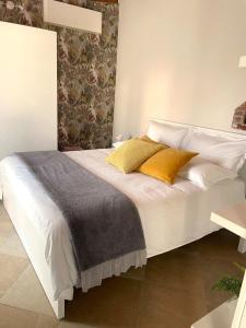 łóżko z białą pościelą i żółtymi poduszkami w obiekcie La Casetta di Angela w mieście Rivarolo Canavese