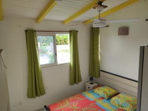 una camera con letto e finestra con tende verdi di Kaz a Roro a Sainte-Anne