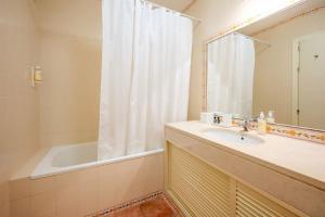 ein Badezimmer mit einer Badewanne, einem Waschbecken und einem Spiegel in der Unterkunft Casa do Jardim- Aroeira in Aroeira