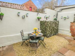 a patio with a table and chairs and a white wall at 2 Bed in York 64455 in Sheriff Hutton