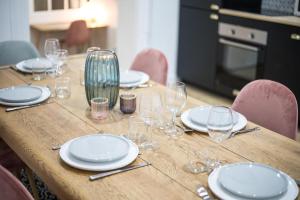 a wooden table with plates and wine glasses on it at Appartement luxueux proche Arc-de-Triomphe - 4P in Paris