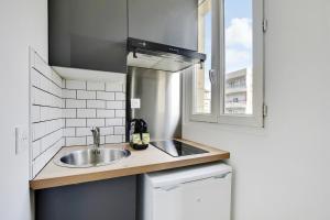een kleine keuken met een wastafel en een raam bij Appartement Suite 43 aux Portes de Paris in Aubervilliers