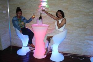 two people sitting on chairs with wine bottles in them at Falcon Lodge (ET) in Bela-Bela